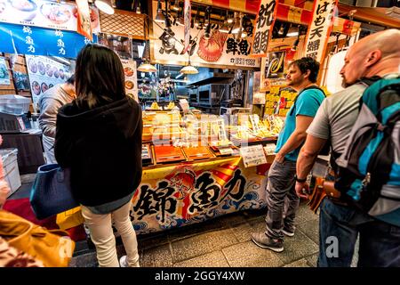 Kyoto, Japan - 16. April 2019: In der Schlange warten die Leute, die auf dem Nishiki-Markt einkaufen, auf Lebensmittelhändler, die Dango-Mochi-Süßigkeiten verkaufen Stockfoto