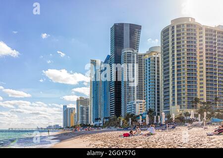 Miami, USA - 19. Januar 2021: Sunny Isles Beach Apartment Condo Hotel Buildings Stadtbild am sonnigen Tag in Florida mit Wolkenkratzern Sand, Wellen auf Sho Stockfoto