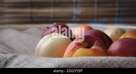 Saftige Früchte in einer Leinentischdecke. Rote, orange, weiße Pflaumen und Aprikosen auf einem Hintergrund. Stockfoto