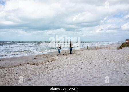 Naples, Florida - 1. Februar 2021: Das Paar steht am Vanderbilt Strand in Florida Stadt durch Sturmwellen mit dramatischen Ozean Golf von Mexiko Ländern Stockfoto