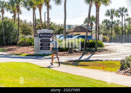 Alys Beach, USA - 15. Januar 2021: Mann läuft im Freien durch Zeichen für Vacasa Büro für Immobilien Ferienwohnungen, Immobilien-Management an der Küste Be Stockfoto