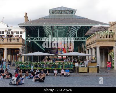 London, Greater London, England, August 24 2021: Auf dem Hauptplatz in Covent Garden vor der Markthalle sitzen Menschen. Stockfoto