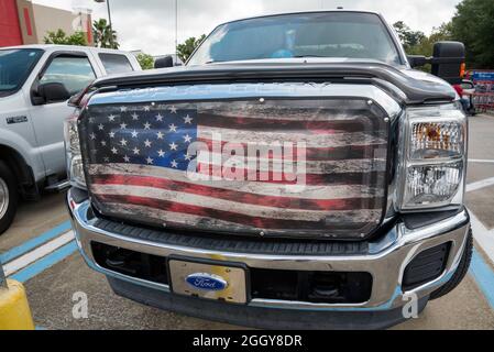 Pickup-Truck mit einer riesigen amerikanischen Flagge in den Kühlergrill eingebettet. Stockfoto