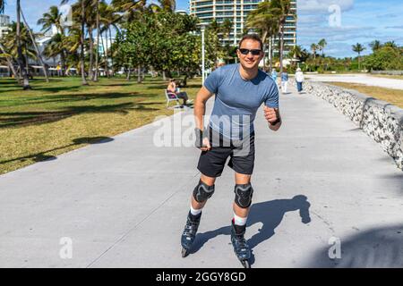 Rollschuhlaufen auf dem Ocean Walk am Lummus Public Park am Ocean Drive in South Beach, Florida mit schützenden Handflächen Stockfoto