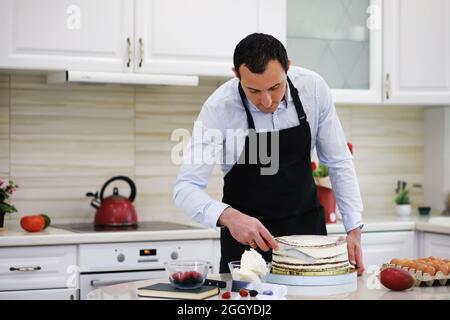 Master Konditor vor einem Schreibtisch. Kochen Desserts zu Hause. Der armenische Mann beschäftigte sich mit der Süßwaren. Stockfoto