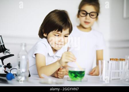 Zwei niedliche Kinder am Chemieunterricht machen Experimente isoliert auf weißem Hintergrund Stockfoto