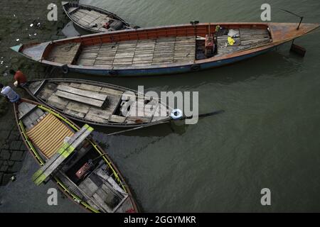 Hölzerne Fischerboote dockten an der Küste an, zwei Männchen saßen an den Rändern Stockfoto