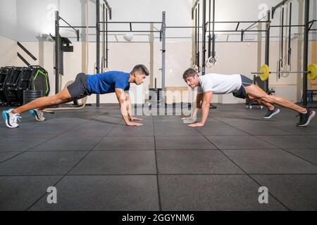 Zwei starke Männer, die Liegestütze im Fitnessstudio machen. Hochwertige Fotos. Stockfoto