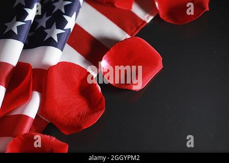 Amerikanische Flagge und Rosenblume auf dem Tisch. Symbol der Vereinigten Staaten von Amerika und rote Blütenblätter. Patriotismus und Erinnerung. Stockfoto