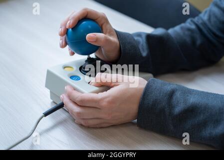 Frau mit zerebraler Lähmung arbeitet an einer spezialisierten Computermaus. Stockfoto