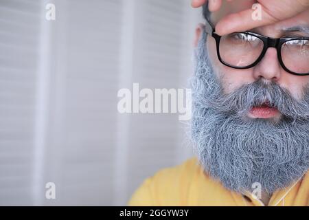 Fröhlicher Hipster-Mann mit weißem Bart. Überraschender Mann mit Brille sieht vorne. Stockfoto