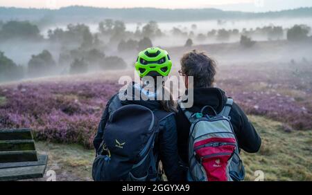 Bispingen, Deutschland. August 2021. Zwei Teilnehmer einer E-Bike-Safari genießen den Sonnenaufgang in der Lüneburger Heide. Die Fotografin Poliza bietet in den Morgenstunden bei Sonnenaufgang geführte E-Bike-Touren durch die Lüneburger Heide an. Quelle: Philipp Schulze/dpa/Alamy Live News Stockfoto