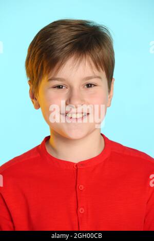 Nahaufnahme Porträt: Trendiger, fröhlicher Teenager-Junge in einem roten Pullover. Er lächelt breit und sieht Auge in Auge. Stockfoto