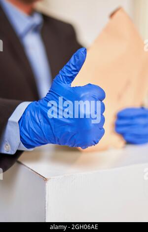 Eine Person in medizinischen Handschuhen wählen. Wahlkonzept. Präsidentschafts- oder Parlamentswahlen. Ein Wähler, der einen Wahlzettel in die Box legt. Wahl Stockfoto