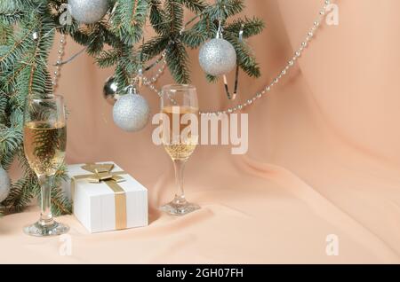 Weihnachten. Eine Neujahrskomposition aus Zweigen eines Weihnachtsbaums, verziert mit silbernen Kugeln, einer Geschenkbox, Sekt-Gläsern. Selektive Stockfoto