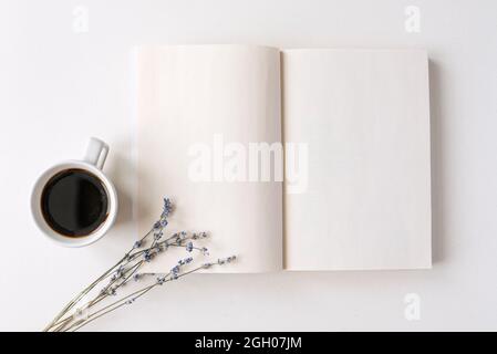 Geöffneter Notizblock, Buch mit weißen leeren Blättern auf einem Schreibtisch. Heißer schwarzer Kaffee, trockenes Lavendelbukett. Morgenstimmung, Platz für Text Stockfoto