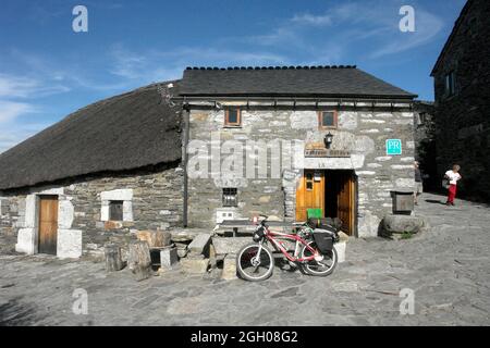 Fahrräder vor den Steinhäusern von Ocebreiro auf der Route Camino de Santiago. Stockfoto
