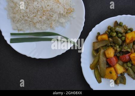 Nahaufnahme von oben von Reis und Matar Paneer Mix Gemüse auf weißem Teller auf schwarzem Hintergrund mit Kopierfläche Stockfoto