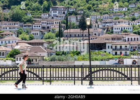 Eine Dame, die auf einem Bürgersteig in einem alten Teil der Stadt berat in albanien spazierengeht Stockfoto
