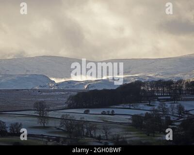 Dramatische Winterlandschaft mit brütenden Sturmwolken über der High Street und Wolkeninversion über verschneiten Shap Fells in Cumbria, England, Großbritannien Stockfoto