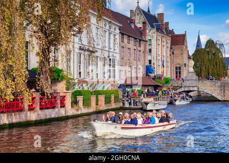 25. September 2018: Brügge, Belgien - Touristen besichtigen in einem Ausflugsboot auf dem Kanal an der Wollestraat-Brücke in Brügge. Stockfoto