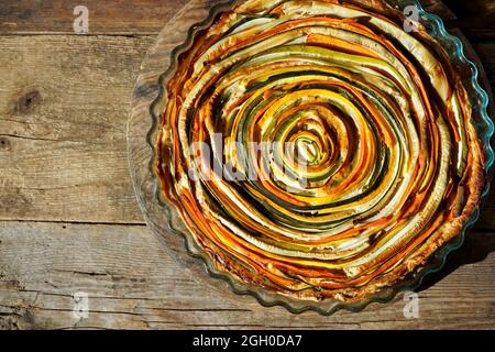 Gemüsekuchen mexikanische Sonne. Runde, offene Torte aus Zucchini, Auberginen und Karotten. Nahaufnahme von oben. Gesunde pflanzliche Lebensmittel. Vegetarismus. Spirale Stockfoto