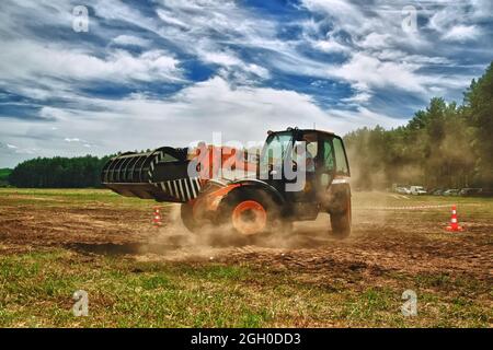 Cherkasy, Ukraine - 12. Juni 2012: Arbeit an rotem Traktorlader JCB . Traktor fährt auf dem Feld auf Waldgrund Stockfoto