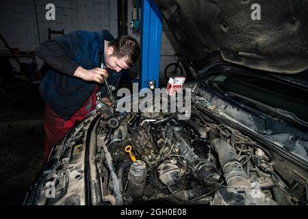 Öffnen Sie in der Reparaturphase in einer Kfz-Mechaniker-Werkstatt echte Pkw-Motoren. Der Mechaniker repariert den Motor. Stockfoto