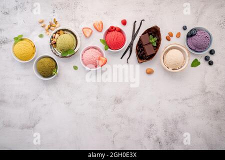 Verschiedene Eis-Aromen in Schale Heidelbeere, grüner Tee, Kokosnuss, Erdbeere und Schokolade Setup auf weißem Stein Hintergrund. Stockfoto