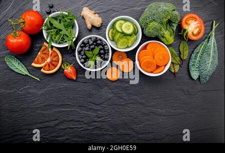 Bunte gesunde Smoothies und Säfte in Flaschen mit frischen tropischen Früchten und Superfoods auf dunklem Stein Hintergrund mit kopieren. Stockfoto