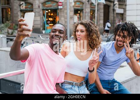 Multiethnische Gruppe von Freunden in einem Park, die sich mit einem Smartphone fotografieren lassen Stockfoto