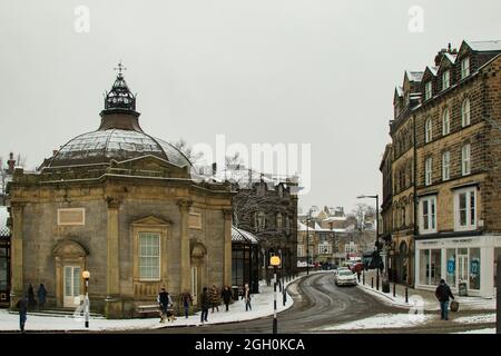 Fußgänger laufen auf einem rutschigen, schneebedeckten Weg entlang des achteckigen Royal Pump Room, Harrogate, North Yorkshire, England, Großbritannien. Stockfoto