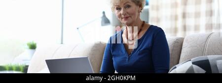 Ältere Frau mit Laptop sitzt auf der Couch Stockfoto