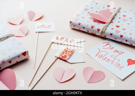Dekorationen und Geschenke zum valentinstag auf einer rosa Oberfläche. Requisiten und verpackte Geschenkboxen. Stockfoto