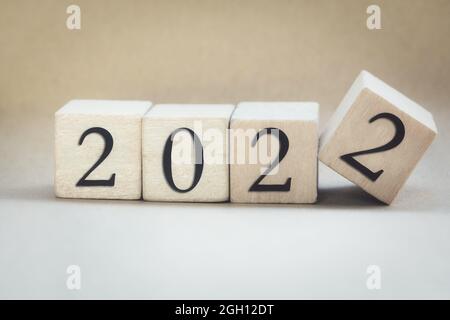 Das Jahr 2022 auf Holzwürfel geschrieben, Finger flipping Jahr zu Jahr, Neujahr Konzept Hintergrund, Start neue natürliche moderne farbige Design stilvoll