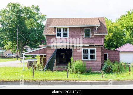 BRADFORD, PA, USA-13 AUGUST 2021: Verlassenes Haus in der Innenstadt, mit fehlenden Türen, kaputten Fenstern, überwuchertem Rasen. Stockfoto