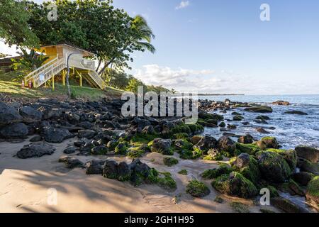 Meereswellen umrunden die mit Algen übersäten Felsen des Ka'anapali Beach in Lahaina, Hawaii. Stockfoto