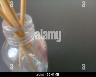 Nahaufnahme von Räucherstäbchen in einem Glasbehälter vor grauem Hintergrund Stockfoto