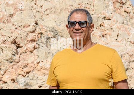 Optimistischer älterer Mann, der draußen steht und lächelt. Nahaufnahme eines glücklichen älteren Mannes, der in die Kamera schaute. Stockfoto