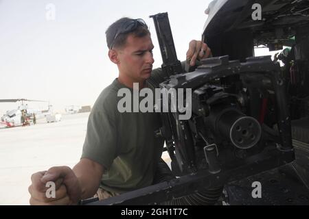 Sgt. Andrew W. Morey stellt ein Maschinengewehr im Kaliber 50 auf einem UH-1Y Huey in Camp Bastion, Afghanistan, Juli 16, bereit. Der 2. Marine Aircraft Wing (Forward) bewegte eine Abtrennung von Hubschraubern vom Marine Light Attack Helicopter Squadron 267 zur Operationsbasis Edinburgh, so dass sich Krankenwagen und die Angriffshubschrauber, die sie unterstützen, am gleichen Ort und zur gleichen Zeit befinden konnten, wenn sie am meisten gebraucht werden. Morey stammt aus Somers, New York, und ist ein Huey-Crew-Chef bei HMLA-267. Stockfoto