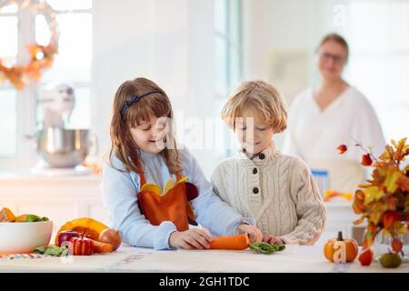 Familie kocht Thanksgiving-Abendessen Großmutter und Kind schnitten Kürbis in der dekorierten Küche. Mutter und Kind kochen im Herbst Gemüse. Stockfoto