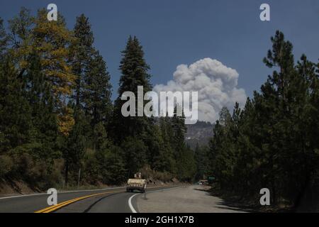 Ein US Army Humvee, der der 270. Military Police Company der California Army National Guard zugewiesen wurde, fährt entlang der US Route 50 durch Silverfork, Kalifornien, in Richtung South Lake Tahoe, während am 1. September 2021 eine Rauchwolke aus dem Caldor-Feuer über den Bergen aufsteigt. CAL Guard aktivierte am 30. August 150 Militärpolizei, um die kalifornische Highway Patrol mit Verkehrskontrollpunkten bei harten Straßensperrungen zu unterstützen, während das Gebiet um South Lake Tahoe evakuiert wird. (USA Foto der Air National Guard von Staff Sgt. Crystal Housman) Stockfoto