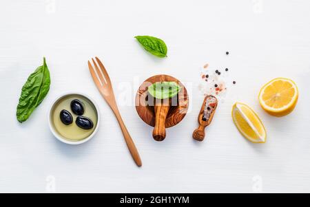 Basilikum Vinaigrette Dressing Zutaten auf weißem Hintergrund mit Holz flach frisches Basilikum Blätter, Zitronenscheibe, natives Olivenöl extra ein Stockfoto