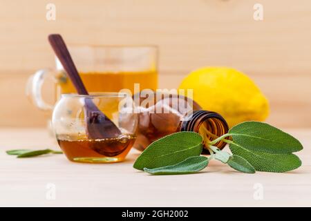 Tasse Kräutertee mit frischem Salbei, Honig und Zitrone auf Holz- Hintergrund. Stockfoto