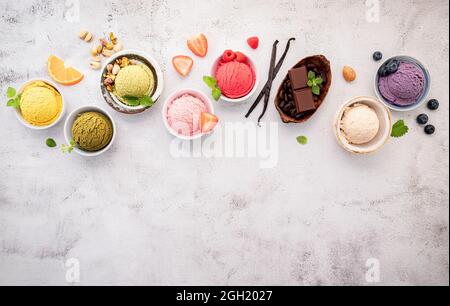 Verschiedene Eis-Aromen in Schale Heidelbeere, grüner Tee, Kokosnuss, Erdbeere und Schokolade Setup auf weißem Stein Hintergrund. Stockfoto