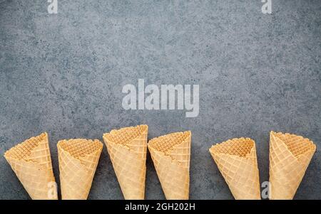 Flach Eistüten Sammlung auf dunklem Stein Hintergrund. Leere knusprige Eiswaffel mit Kopie Raum für Süßigkeiten Menü Design. Stockfoto