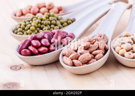 Auswahl an Bohnen und Linsen in Löffel aus Holz auf Holz- Hintergrund. mung Bean, Erdnuß, Soja, rote Kidney-bohnen, Schwarze Bohne, roten Bohnen und Braun Stockfoto