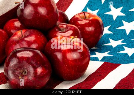 Haufen roter Äpfel auf einem Baumwolltuch mit weißen Sternen auf blauem Hintergrund und roten und weißen Streifen. Stockfoto