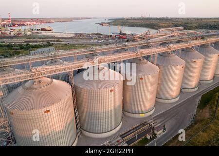 Odessa, Ukraine - Аugust 14, 2021: Getreideterminals des modernen Handelshafens. Silos zur Lagerung von Getreide in Strahlen untergehenden Sonnenlichtes, Draufsicht von Quadco Stockfoto