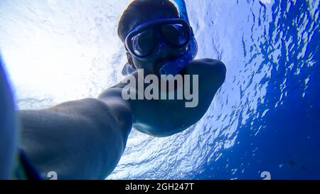 Ein Mann ist dabei, in einer Maske und einem Atemschlauch in die Tiefen des Roten Meeres zu schnorcheln Stockfoto